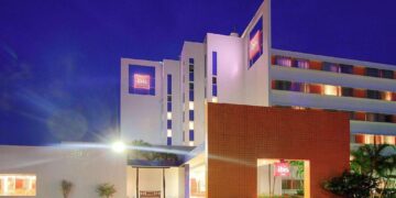 Edificio hotelero de múltiples niveles gestionado por Accor, con la reconocida insignia ibis en su fachada, destacado por su diseño moderno e iluminación arquitectónica nocturna que resalta su presencia urbana. La entrada principal, marcada por una elegante estructura naranja y rodeada de jardín cuidadosamente seleccionada, ofrece una bienvenida sofisticada y exclusiva. Esta propiedad representa una oportunidad excepcional para inversores o compradores que buscan activos inmobiliarios premium en el sector hotelero internacional.