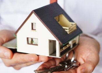 Una persona sostiene una maqueta exclusiva de vivienda junto a un juego de llaves, simbolizando la adquisición o alquiler de inmuebles en un contexto dinámico del mercado residencial. La escena transmite oportunidades excepcionales en el sector inmobiliario premium, donde cada detalle marca la diferencia para inversores y compradores exigentes que buscan propiedad con alto valor agregado. El fondo desenfocado enfatiza el protagonismo del inmueble y la experiencia personalizada que distingue a las mejores inversiones patrimoniales.