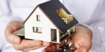 Una persona sostiene una maqueta exclusiva de vivienda junto a un juego de llaves, simbolizando la adquisición o alquiler de inmuebles en un contexto dinámico del mercado residencial. La escena transmite oportunidades excepcionales en el sector inmobiliario premium, donde cada detalle marca la diferencia para inversores y compradores exigentes que buscan propiedad con alto valor agregado. El fondo desenfocado enfatiza el protagonismo del inmueble y la experiencia personalizada que distingue a las mejores inversiones patrimoniales.