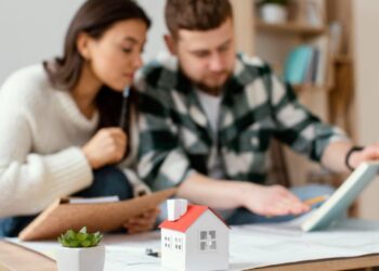 Dos ejecutivos se reúnen en un entorno elegante y privado para analizar detalladamente documentos relevantes, evaluando oportunidades de inversión inmobiliaria. Sobre la mesa destacan una maqueta arquitectónica y elementos decorativos discretos, subrayando el enfoque en propiedades residenciales de alto valor y proyectos con potencial de plusvalía superior. Esta escena refleja el rigor profesional y la visión estratégica que caracterizan a quienes participan en el segmento premium del mercado inmobiliario.