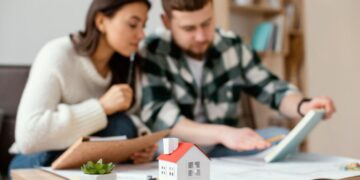 Dos ejecutivos se reúnen en un entorno elegante y privado para analizar detalladamente documentos relevantes, evaluando oportunidades de inversión inmobiliaria. Sobre la mesa destacan una maqueta arquitectónica y elementos decorativos discretos, subrayando el enfoque en propiedades residenciales de alto valor y proyectos con potencial de plusvalía superior. Esta escena refleja el rigor profesional y la visión estratégica que caracterizan a quienes participan en el segmento premium del mercado inmobiliario.