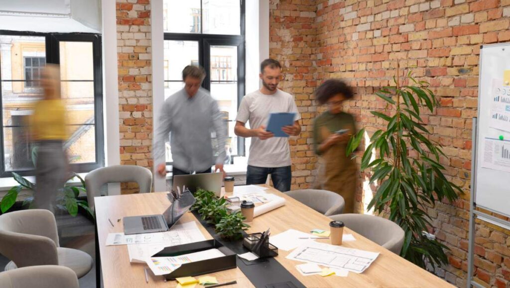 Un equipo de profesionales colabora en un exclusivo espacio de oficinas, diseñado con elegantes muros de ladrillo expuesto que reflejan la sofisticación y el vanguardismo del coworking premium en la Ciudad de México. La oficina ofrece amplios ventanales que inundan los ambientes con luz natural, integrando elementos modernos como pizarras blancas funcionales y detalles cuidadosamente seleccionados —incluyendo plantas ornamentales y una zona de café— para fomentar la productividad y el networking. Este entorno representa una oportunidad única para inversores o compradores que buscan espacios corporativos de alto nivel, ideales para empresas visionarias que valoran imagen, ubicación estratégica y un ambiente inspirador.