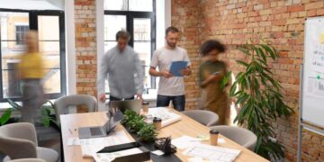 Un equipo de profesionales colabora en un exclusivo espacio de oficinas, diseñado con elegantes muros de ladrillo expuesto que reflejan la sofisticación y el vanguardismo del coworking premium en la Ciudad de México. La oficina ofrece amplios ventanales que inundan los ambientes con luz natural, integrando elementos modernos como pizarras blancas funcionales y detalles cuidadosamente seleccionados —incluyendo plantas ornamentales y una zona de café— para fomentar la productividad y el networking. Este entorno representa una oportunidad única para inversores o compradores que buscan espacios corporativos de alto nivel, ideales para empresas visionarias que valoran imagen, ubicación estratégica y un ambiente inspirador.