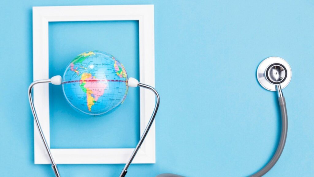 Un globo terráqueo en miniatura, delicadamente sostenido por un estetoscopio dentro de un marco blanco rectangular, destaca sobre un fondo azul claro. Esta imagen representa la visión global y el cuidado minucioso que definen a las inversiones inmobiliarias premium: seguridad, precisión y alcance internacional para satisfacer las expectativas de los compradores más exigentes.