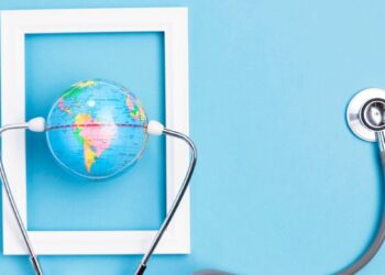 Un globo terráqueo en miniatura, delicadamente sostenido por un estetoscopio dentro de un marco blanco rectangular, destaca sobre un fondo azul claro. Esta imagen representa la visión global y el cuidado minucioso que definen a las inversiones inmobiliarias premium: seguridad, precisión y alcance internacional para satisfacer las expectativas de los compradores más exigentes.