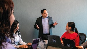 En una moderna sala de conferencias de ambiente sobrio y elegante, un ejecutivo vestido con traje dirige una sesión exclusiva sobre inteligencia estratégica y análisis de mercado enfocado en el sector inmobiliario premium. Frente a él, tres inversionistas evalúan información clave desde sus laptops. Dos participantes atienden atentamente los datos expuestos, mientras la tercera registra los puntos más relevantes en su computadora portátil. La escena refleja profesionalismo, confidencialidad y dedicación absoluta al desarrollo de oportunidades excepcionales para capitales exigentes dentro del segmento exclusivo del inmobiliario.