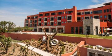 Este exclusivo edificio de diseño contemporáneo, de varios niveles y estructura en tonos rojo y beige, destaca por sus amplios ventanales y terrazas privadas que favorecen la luminosidad natural y las vistas panorámicas. Ubicada en Pueblo Bonito Vantage, la propiedad se integra a un sofisticado entorno paisajístico que incorpora un elegante jardín seco boutique, una propuesta única de estilo con cactus seleccionados, formaciones rocosas cuidadosamente dispuestas y una escultura arbórea distintiva. Todo ello bajo el marco de cielos despejados, creando un ambiente inigualable ideal para clientes exigentes en busca de inversión inmobiliaria premium o una residencia exclusiva con carácter y distinción.