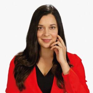 Mujer de presencia impecable, con cabello oscuro y vestimenta elegante en tonos rojos y negros, se presenta ante un fondo neutro con una actitud decidida y mirada directa. Su posee seguridad transmite y dominio en el ámbito de la edificación premium, integrando conocimientos avanzados en construcción sostenible bajo los más altos estándares LEED. Representa la nueva generación de liderazgo inmobiliario orientado al valor duradero, eficiencia energética e inversión responsable.