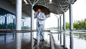 Un hombre vestido con un impecable traje azul claro camina sobre un elegante pavimento mojado, resguardado bajo una amplia estructura techada. Sostiene un paraguas y conversa por teléfono, inmerso en la dinámica de la ciudad. Esta escena urbana ilustra cómo el cambio climático está transformando los hábitos cotidianos y evidencia la importancia de invertir en desarrollos inmobiliarios premium que priorizan el confort, la protección y el diseño adaptativo ante nuevas condiciones climáticas. En este contexto, las propiedades exclusivas que integran espacios cubiertos y soluciones arquitectónicas innovadoras adquieren mayor valor para inversores y compradores exigentes que buscan seguridad, funcionalidad y distinción en sus inversiones inmobiliarias.