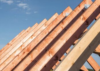 Vista detallada de las cerchas de madera bajo construcción, enmarcadas contra un cielo despejado. Las vigas—perfectamente alineadas y aseguradas con placas metálicas—evidencian prácticas constructivas sostenibles y duraderas. Esta meticulosa atención a la calidad estructural garantiza una inversión segura y atractiva para quienes buscan excelencia arquitectónica en el mercado inmobiliario premium.