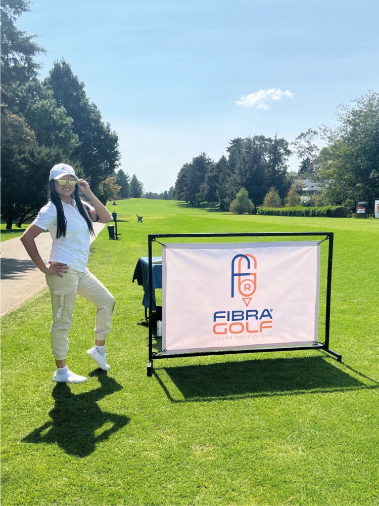 Una mujer con vestimenta blanca y gorra se encuentra en un exclusivo campo de golf junto a un letrero que indica "FIBRA GOLF", poniendo en primer plano el creciente potencial del turismo de golf en México. El entorno, rodeado de áreas verdes y bajo un cielo despejado, subraya la sofisticación y atractivo natural de estos desarrollos inmobiliarios premium, ideales para inversores y compradores que buscan activos distinguidos con alta proyección dentro del mercado nacional e internacional.