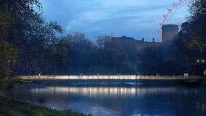 Pasarela peatonal de diseño exclusivo por Foster + Partners, que se extiende sobre un río sereno en un entorno natural cuidadosamente preservado. Al anochecer, la pasarela conecta elegancia arquitectónica y funcionalidad contemporánea con vistas inigualables: el skyline urbano, el Monumento a la Reina Isabel II y una emblemática noria completan el horizonte bajo un cielo azul crepuscular. Un enclave excepcional que ofrece valor patrimonial, calidad de vida superior e inspiración para inversiones inmobiliarias premium.