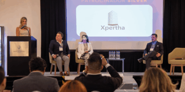 En el marco del exclusivo congreso REBS Puebla, cuatro destacados profesionales del sector inmobiliario se presentan en el escenario: uno de ellos lidera la conversación desde el podio, mientras los otros tres expertos acompañan la sesión como panelistas. En una pantalla principal se exhibe el logotipo de Xpertha junto a la distinción de "Patrocinador Silver", subrayando su compromiso con la excelencia y la innovación en bienes raíces premium. Ante una audiencia selecta y atenta, se exponen atractivas oportunidades de inversión diseñadas para satisfacer las expectativas de inversores visionarios y compradores exigentes en busca de proyectos inmobiliarios exclusivos y altamente rentables.