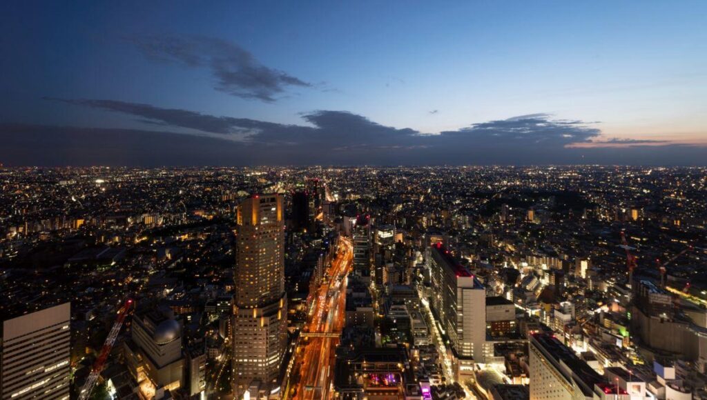 Vista aérea de la ciudad al anochecer, con edificios y avenidas iluminadas, destacando una torre central de gran altura. Esta imagen captura las alcaldías más exclusivas y cotizadas de la Ciudad de México, reconocidas por su alta demanda en el mercado premium de renta de departamentos. El cielo en transición suave subraya el dinamismo urbano y la sofisticación del entorno, atributos clave para inversionistas y compradores que buscan inmuebles excepcionales en las zonas más valoradas de CDMX.