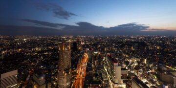 Vista aérea de la ciudad al anochecer, con edificios y avenidas iluminadas, destacando una torre central de gran altura. Esta imagen captura las alcaldías más exclusivas y cotizadas de la Ciudad de México, reconocidas por su alta demanda en el mercado premium de renta de departamentos. El cielo en transición suave subraya el dinamismo urbano y la sofisticación del entorno, atributos clave para inversionistas y compradores que buscan inmuebles excepcionales en las zonas más valoradas de CDMX.