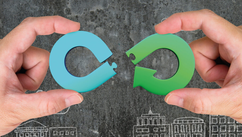 Dos manos sostienen piezas circulares de rompecabezas en azul y verde, diseñadas en forma de flechas que encajan perfectamente. El fondo oscuro, realzado por siluetas blancas de edificios, representa la innovadora iniciativa "Reciclar para Construir" de Saint-Gobain en Santa Catarina. Este proyecto integra sostenibilidad y vanguardia arquitectónica, ofreciendo desarrollos inmobiliarios premium que optimizan recursos y elevan los estándares medioambientales-una propuesta exclusiva para inversores y compradores que buscan excelencia, responsabilidad social y plusvalía en cada metro cuadrado.