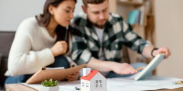 Una mujer y un hombre se reúnen en una mesa en México analizando cuidadosamente documentación relevante y notas estratégicas. Al frente, un modelo arquitectónico de vivienda premium y una planta ornamental destacan el enfoque de la conversación: la evaluación del valor inmobiliario y la revisión de documentos clave, posiblemente relacionados con INBAPREVI. Este escenario refleja el compromiso con procesos rigurosos de análisis para la adquisición o inversión en propiedades exclusivas, asegurando decisiones informadas dentro del sector inmobiliario de alto nivel.