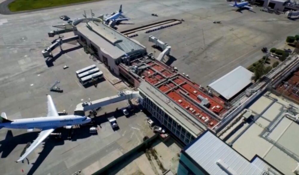 Vista aérea de una terminal aeroportuaria operada por Aeropuertos de México, que refleja un sólido compromiso con la inversión y la modernización. La imagen destaca una infraestructura de vanguardia, con múltiples aeronaves en posición, puentes de embarque eficientes, vehículos de servicio especializados y edificios aeroportuarios modernos, integrados a pistas totalmente pavimentadas. Este entorno estratégico representa una oportunidad exclusiva para inversores y compradores exigentes que buscan activos premium en el sector inmobiliario aeroportuario mexicano.