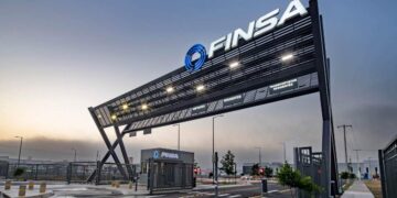 Acceso principal a parque industrial de alta gama, con un imponente letrero negro FINSA iluminado, caseta de seguridad equipada, barreras automáticas y vialidades completamente pavimentadas. Esta infraestructura moderna refleja los más altos estándares inmobiliarios para 2024 y subraya el compromiso con la Certificación LEED, garantizando eficiencia, sostenibilidad y máxima seguridad para inversionistas y compradores que exigen excelencia.