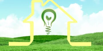 Una silueta dorada de una residencia se alza sobre suaves colinas verdes, bajo un cielo azul claro. En su interior, una luminaria verde con un brote simboliza el compromiso con la sustentabilidad en proyectos residenciales premium y comunidades planeadas. Esta representación visual destaca el enfoque en soluciones ecológicas y entornos exclusivos pensados para inversores y compradores que privilegian eficiencia energética, innovación arquitectónica y calidad de vida superior.